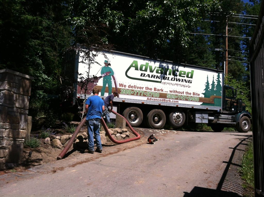 Advanced Bark Blowing blower truck and crew member blowing landscape bark into a residential bed